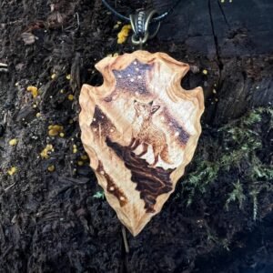 wood-carved arrowhead pendant featuring a fox looking at the aurora borealis