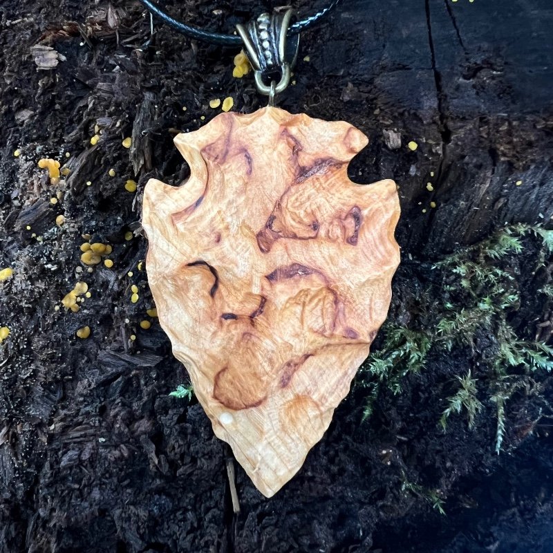 backside of a wood-carved arrowhead with chiseled texture
