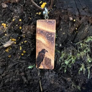 Rectangular wooden pendant featuring a Raven gazing up at the Northern Lights