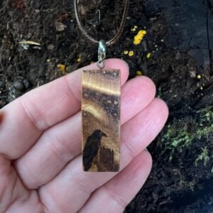 Rectangular wooden pendant featuring a Raven gazing up at the Northern Lights