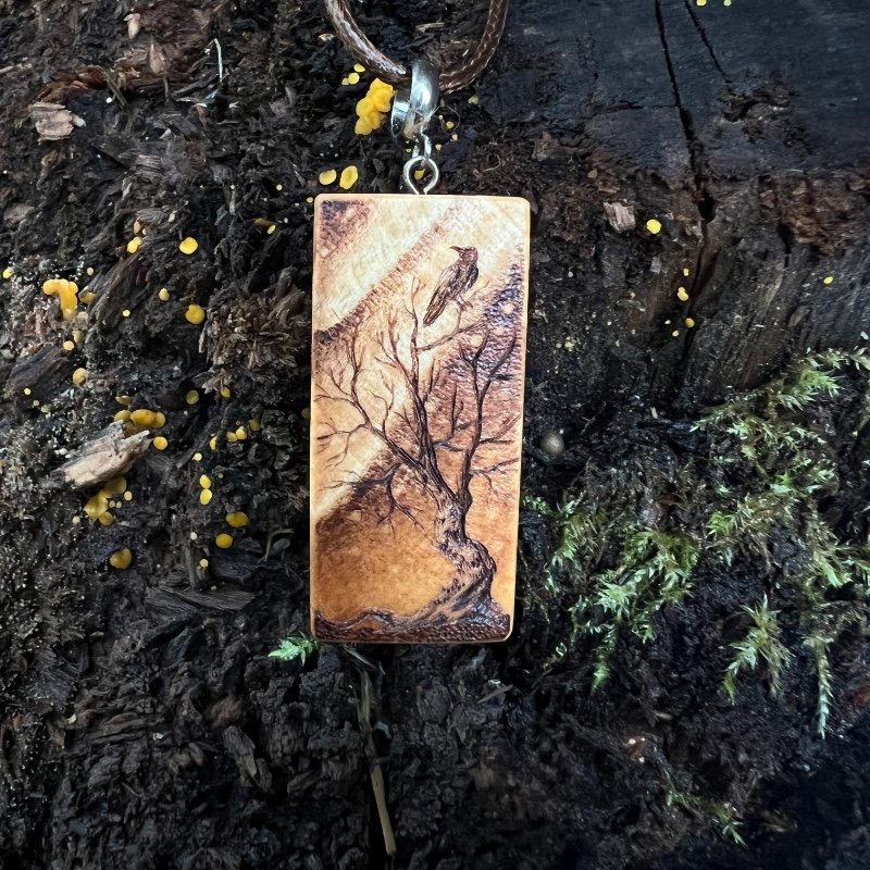 Rectangular wooden pendant featuring a gnarly tree with a bird gazing up at the Northern Lights