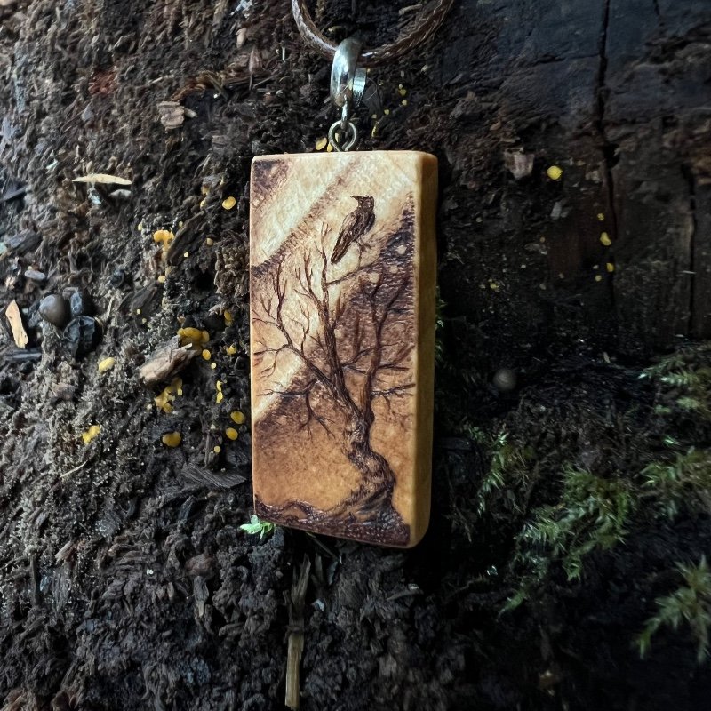 Rectangular wooden pendant featuring a gnarly tree with a bird gazing up at the Northern Lights