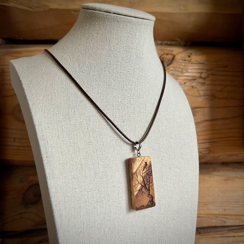 Wooden pendant on a bust, to show how it will hang when wearing it.